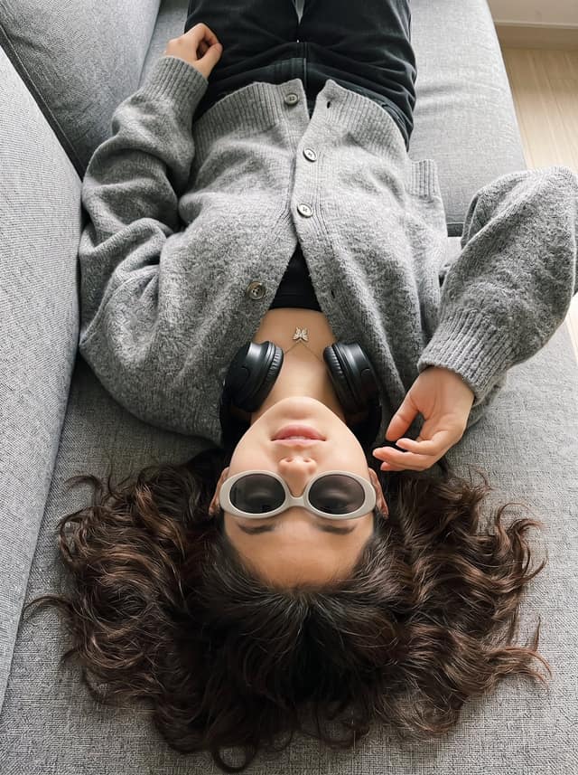 نمونهٔ 倒卧沙发俯拍复古针织衫少女写真提示词